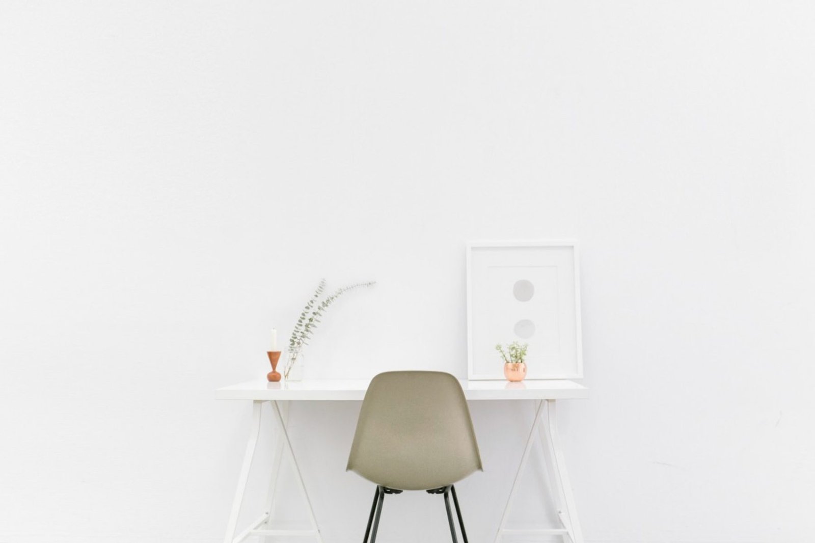 Escritorio y silla en un cuarto blanco minimalista, con piso reflectante